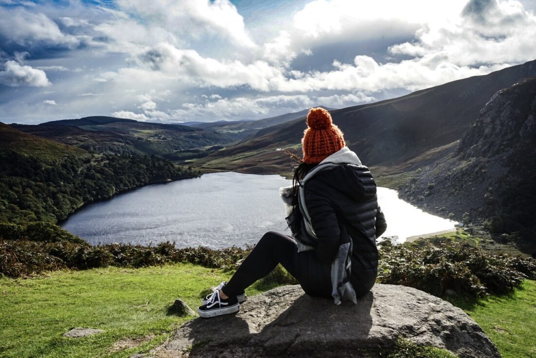 woman sitting on a rock looking at a lake in a valley in Wicklow Ireland